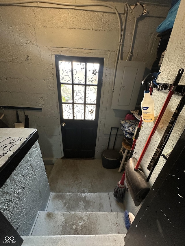 doorway featuring concrete block wall, electric panel, and concrete floors