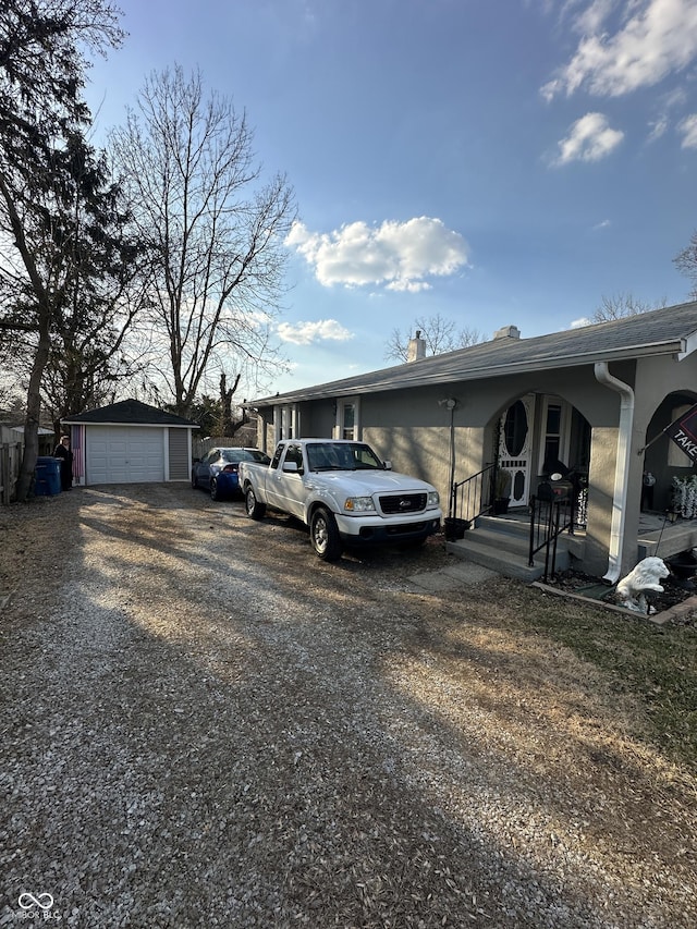 view of property exterior featuring a detached garage, driveway, an outdoor structure, and a chimney