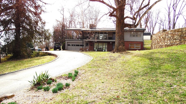 view of front of home featuring aphalt driveway, a garage, a chimney, and a front yard