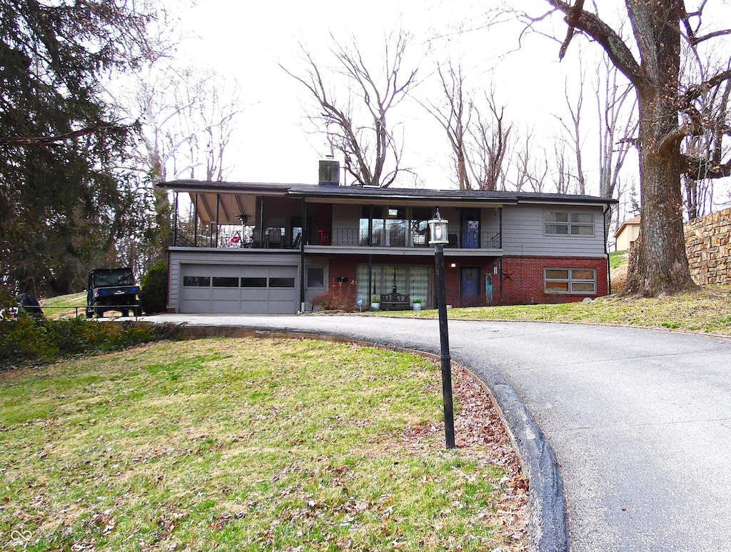 view of front of home with an attached garage, a front yard, central AC unit, a balcony, and driveway