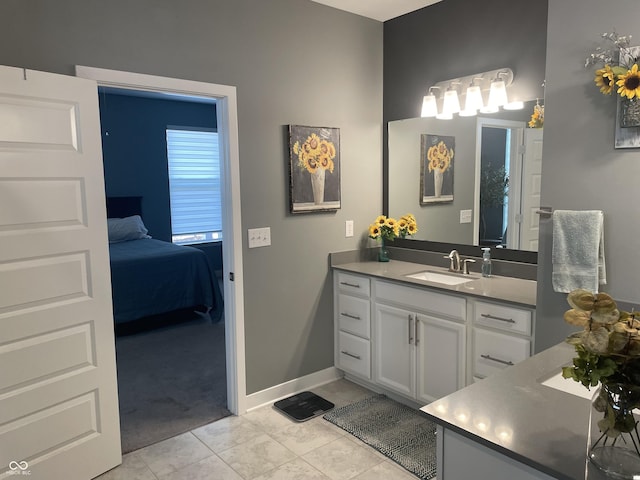 bathroom featuring vanity, tile patterned floors, baseboards, and ensuite bathroom