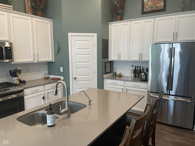 kitchen featuring a sink, a kitchen breakfast bar, white cabinets, and stainless steel appliances