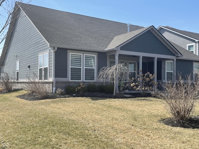 back of property featuring a yard, brick siding, covered porch, and a shingled roof