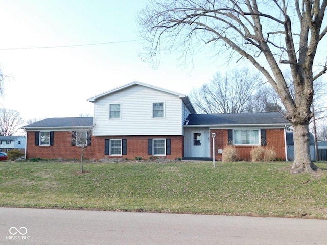 tri-level home featuring brick siding and a front yard