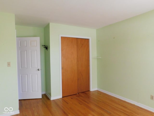 unfurnished bedroom with wood finished floors, a closet, and baseboards