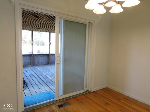 interior space featuring visible vents, baseboards, an inviting chandelier, and wood finished floors