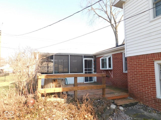 back of property with a wooden deck, brick siding, and a sunroom