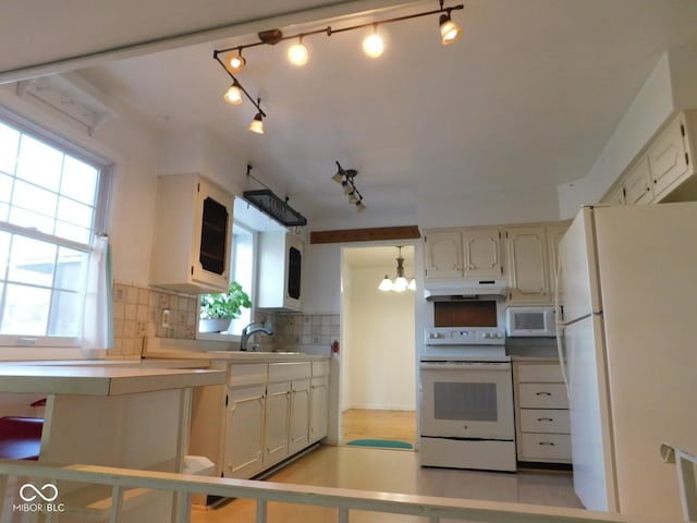 kitchen featuring white appliances, a wealth of natural light, backsplash, and under cabinet range hood