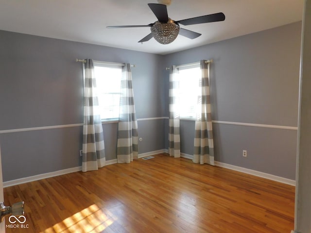 empty room featuring wood finished floors, baseboards, and ceiling fan