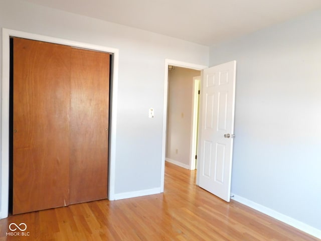 unfurnished bedroom with a closet, light wood-style flooring, and baseboards