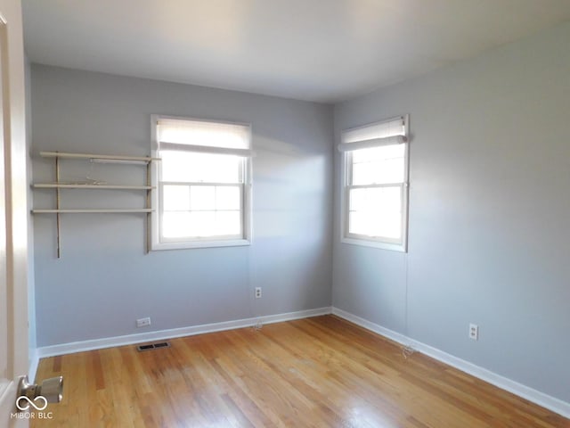 unfurnished room featuring wood finished floors, visible vents, and baseboards