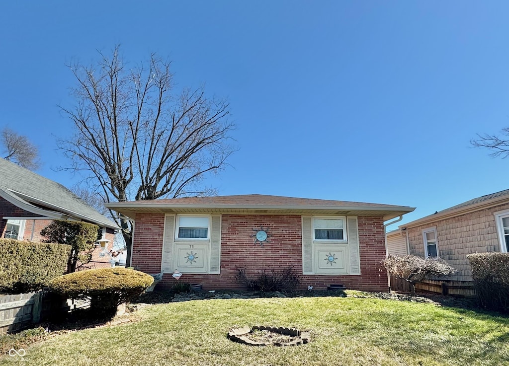 view of front of home with brick siding, a front yard, and fence