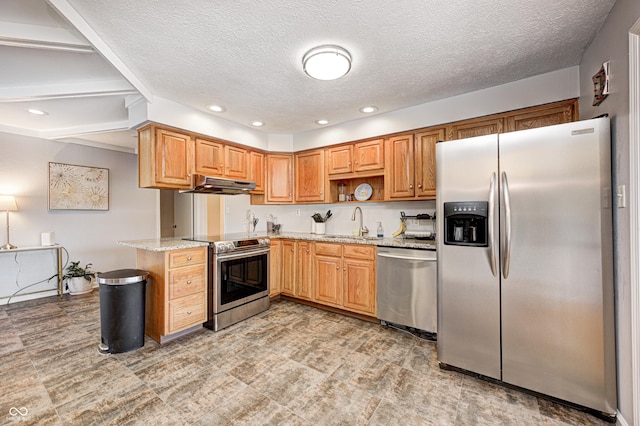 kitchen featuring under cabinet range hood, light stone counters, recessed lighting, stainless steel appliances, and a sink