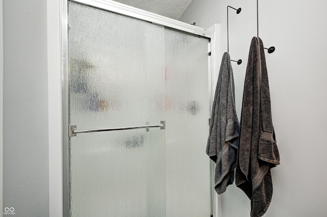 bathroom with a textured ceiling and a stall shower