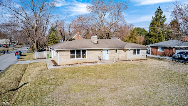 back of property featuring a lawn, a chimney, and fence