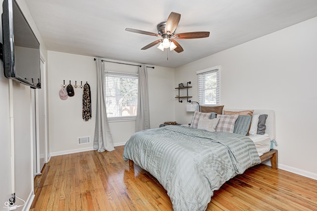 bedroom featuring light wood-style flooring, multiple windows, baseboards, and visible vents