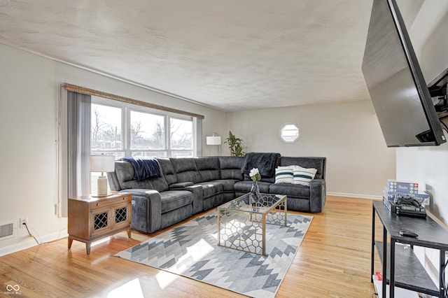 living area featuring visible vents, baseboards, and wood finished floors