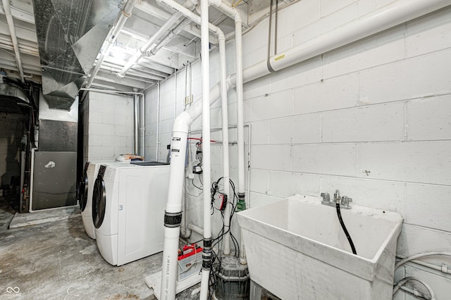 clothes washing area with a sink, heating unit, laundry area, and washer and clothes dryer