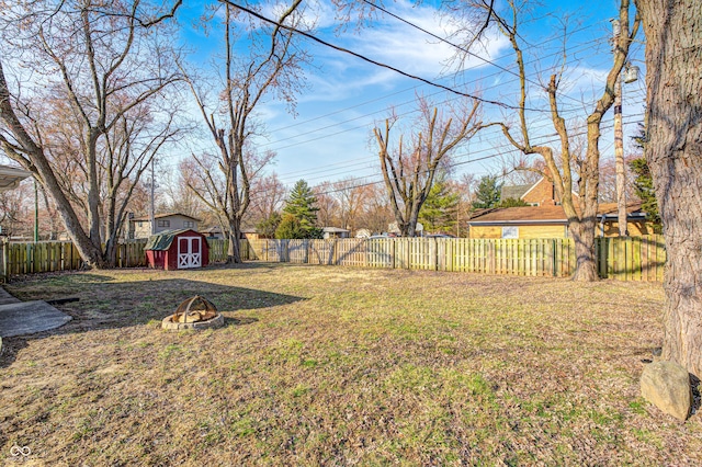 view of yard with a fenced backyard, a storage unit, a fire pit, and an outdoor structure