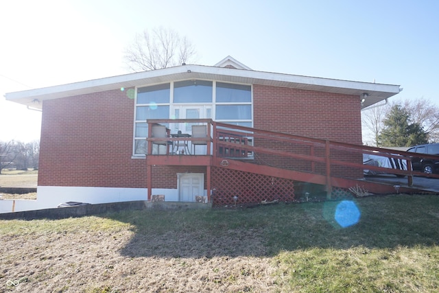 rear view of property with brick siding, a deck, and a yard