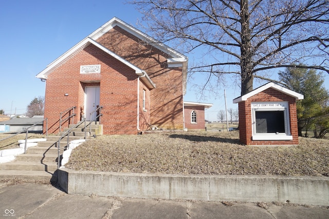 view of property exterior with an outdoor structure and brick siding