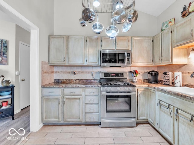 6556 Aintree Ter, Indianapolis, IN 46250 - kitchen with a sink, stainless steel appliances, light wood finished floors, vaulted ceiling, and backsplash