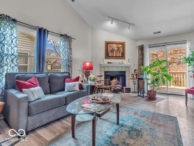 6556 Aintree Ter, Indianapolis, IN 46250 - living room featuring a fireplace, track lighting, visible vents, vaulted ceiling, and wood finished floors