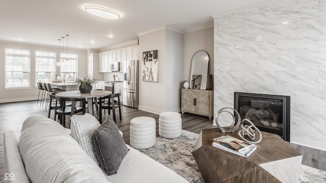 living room featuring crown molding, baseboards, dark wood finished floors, recessed lighting, and a fireplace