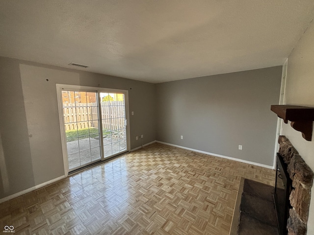 unfurnished living room with baseboards, visible vents, and a textured ceiling