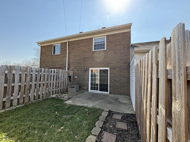 back of house featuring a yard, brick siding, a fenced backyard, and a patio area