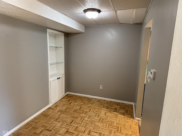 spare room with a paneled ceiling and baseboards