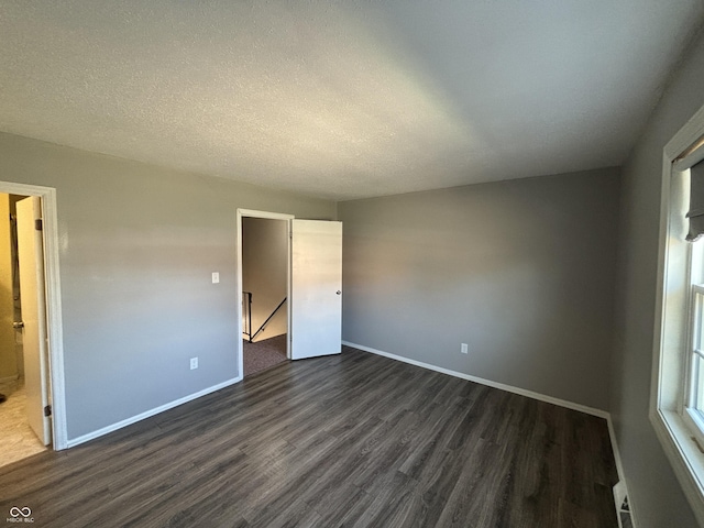 unfurnished bedroom with dark wood finished floors, baseboards, and a textured ceiling