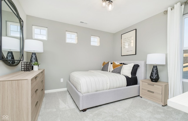 bedroom featuring visible vents, multiple windows, light colored carpet, and baseboards