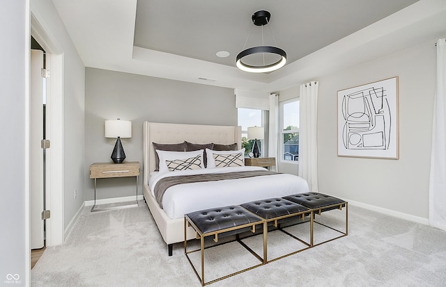 bedroom featuring light carpet, visible vents, a raised ceiling, and baseboards