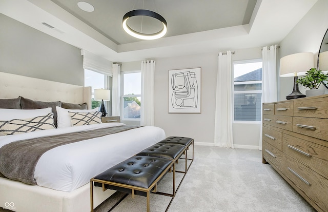 bedroom featuring light carpet, visible vents, baseboards, and a tray ceiling