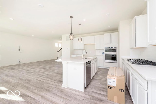 kitchen featuring open floor plan, light wood-style flooring, stainless steel appliances, and a sink