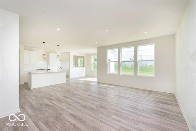 unfurnished living room with recessed lighting, baseboards, and light wood finished floors