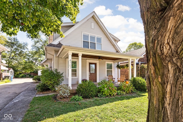 view of front of home featuring concrete driveway, covered porch, and a front lawn