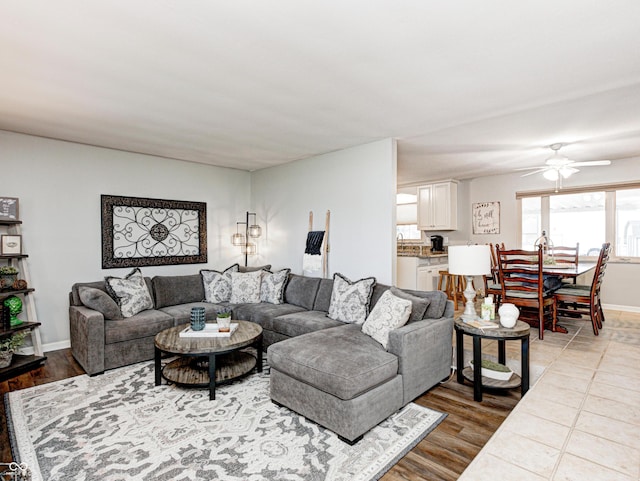 living room featuring wood finished floors, a ceiling fan, and baseboards