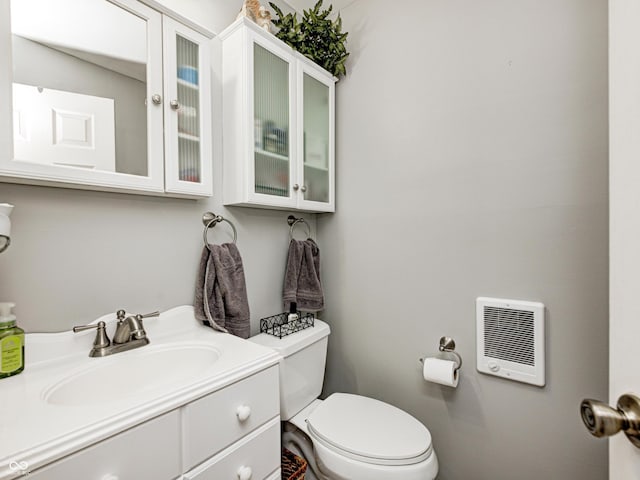 half bathroom featuring toilet, heating unit, and vanity