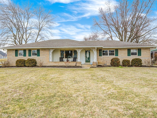 single story home featuring stone siding, roof with shingles, covered porch, and a front yard