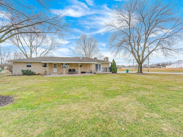 view of front of property featuring a patio, a chimney, and a front yard