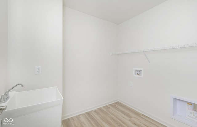 laundry area featuring baseboards, washer hookup, laundry area, light wood-style flooring, and a sink