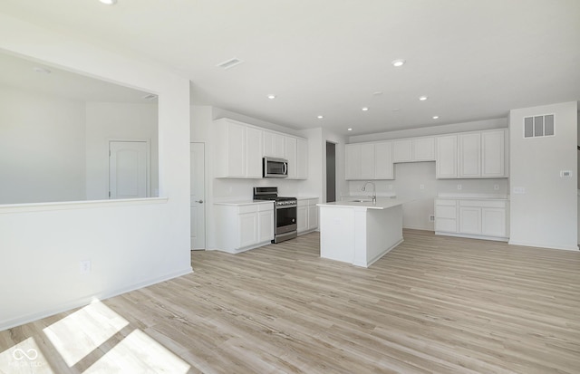 kitchen with light wood finished floors, visible vents, white cabinets, and appliances with stainless steel finishes