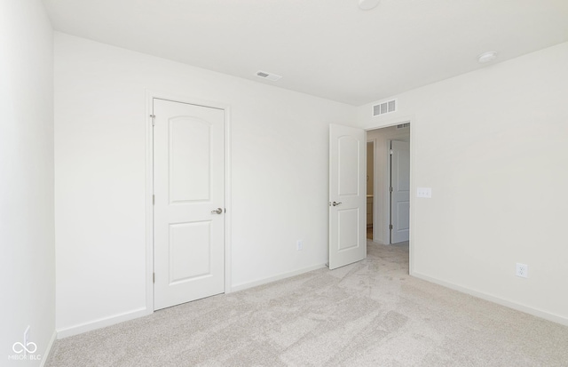 unfurnished bedroom featuring light colored carpet, visible vents, and baseboards