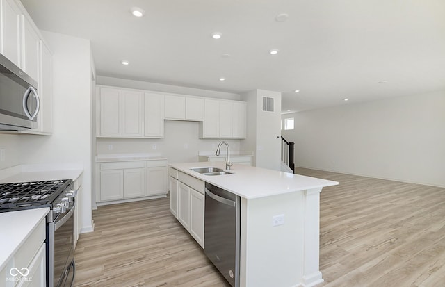 kitchen featuring visible vents, a sink, light wood-style flooring, appliances with stainless steel finishes, and a kitchen island with sink