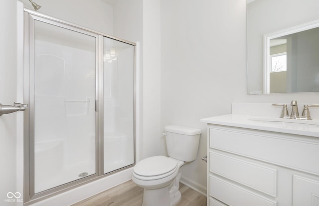 bathroom featuring a shower stall, baseboards, toilet, wood finished floors, and vanity