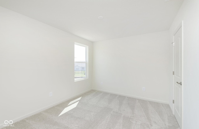 unfurnished room with baseboards and light carpet