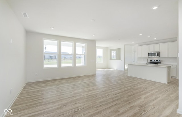 unfurnished living room with visible vents, recessed lighting, light wood-type flooring, and baseboards