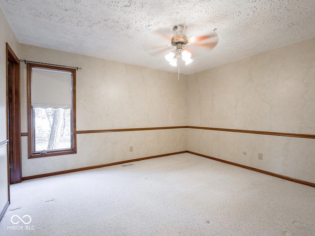 empty room featuring carpet flooring, ceiling fan, a textured ceiling, and visible vents